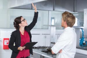 woman undergoing inspection in restaurant kitchen with chef