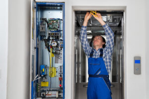 Technician Repairing Control Panel Of Broken Elevator